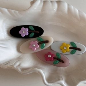 Set of four jelly-colored flower hair clips with rhinestones in a white shell dish