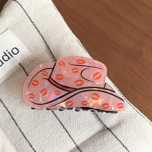 Detail view of pink pearlescent cowboy hat hair claw with red lip prints and glossy finish