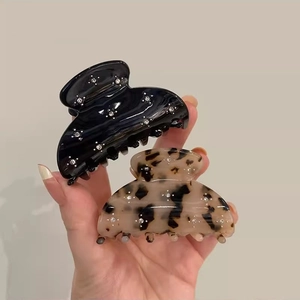 Dettaglio di mollette per capelli in acetato nero e tartarugato con strass brillanti