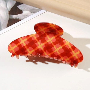 Close-up of a large red and yellow plaid hair claw clip with glossy finish on a white surface