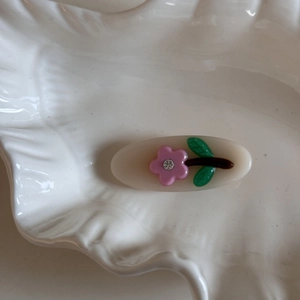Close-up of jelly color flower hair clip with rhinestones on a white textured tray