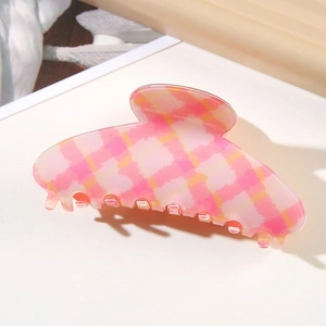Detailed macro view of a pink and yellow checkered PVC hair claw clip with a glossy finish