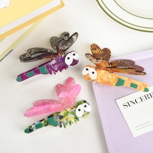 Detail view of colorful dragonfly hair claws made of acetate with textured wings