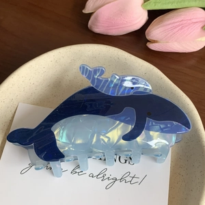 Detail of whale hair claw clip with blue acetate finish and aurora luster on beige plate