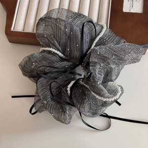 Macro shot of grey organza scrunchie with white pearl accents and black ribbons