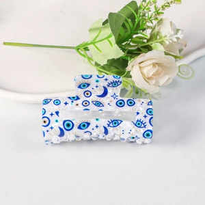 Detail of blue and white rectangle hair claw clip with evil eye and moon patterns