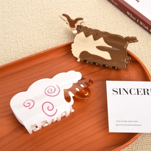 Set of cute acetate animal claw clips with cow and sheep designs on a wooden tray