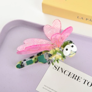 Close-up of a decorative dragonfly hair claw with pink wings and tortoise shell body