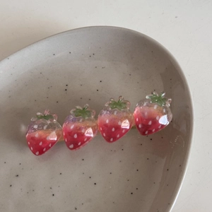 Dettaglio di un fermaglio per capelli a fragola con decorazioni in resina su vassoio in ceramica