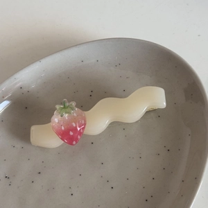 Dettaglio molletta per capelli ondulata crema con fragola su vassoio in ceramica