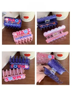 Detail showing glitter acrylic hair claw with 'CHAOS COORDINATOR' text and heart arrow