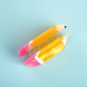 Macro shot of pencil-shaped hair claw clip in gradient pastel colors on a blue background