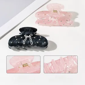 Macro view of marble acetate hair claw with rhinestone bow and durable metal spring