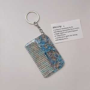 Detail of blue marble acetate hair comb keychain with silver metal ring and prop card