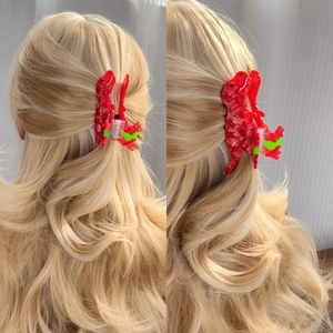 Red T-Rex dinosaur hair claw clip made of acetate on blonde curly hair, side view