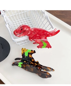 Detail view of red and tortoiseshell acetate dinosaur hair claws with vibrant green accents