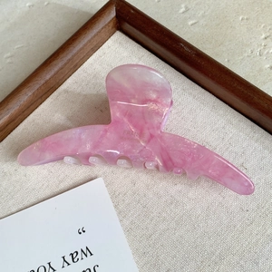 Detail view of pink marble acetate hair claw clip featuring France Handmade text