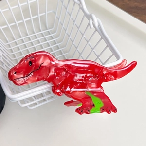 Detail view of red marble acetate dinosaur hair claw clip with green accents