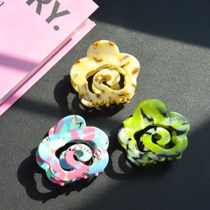 Detailed close-up of acetate flower hair claws in marble beige, lime, and multicolor