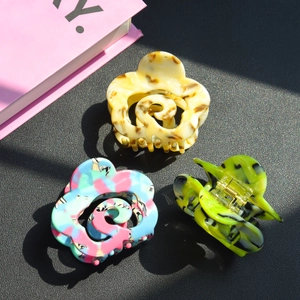 Three-piece floral acetate hair claw set with marbled patterns in natural sunlight