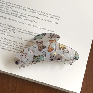 Gros plan sur une pince à cheveux nacrée avec motifs de chats mignons sur un livre ouvert