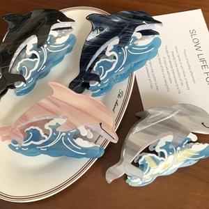Elegant dolphin-shaped acetate hair claws in various colors displayed on a white plate
