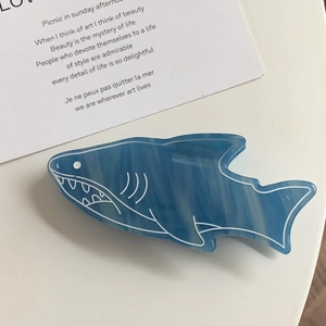 Macro shot of blue acetate shark hair claw clip with marble texture on white table