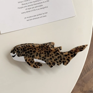 Detailed view of a leopard print acetate shark hair claw clip on a cream surface