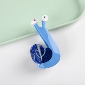 Dettaglio ravvicinato di una molletta per capelli blu a forma di lumaca con motivi a cuore