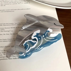 Detailed macro view of a dolphin-shaped acetate hair claw with blue ocean wave patterns