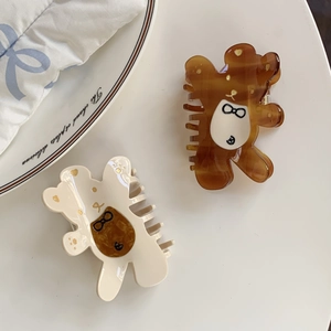 Pinces à cheveux mignonnes en forme d'ours en acétate ambre et crème sur une assiette