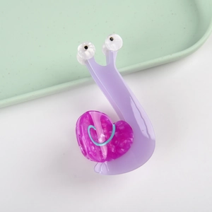 Dettaglio della molletta in acetato a forma di lumaca con guscio a cuore in viola