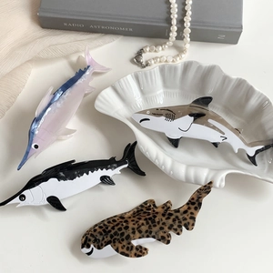 Shark and dolphin shaped acetate hair claws in various ocean-inspired patterns
