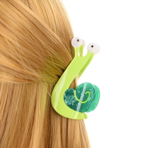 Dettaglio di un fermaglio per capelli a chiocciola in acetato verde sui capelli