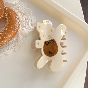 Détail de la pince à cheveux ours blanc crème avec motif ambre brun dans un décor raffiné