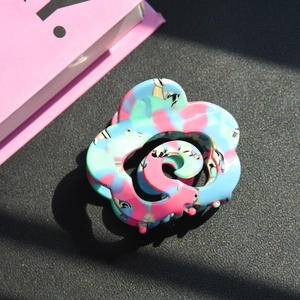 Macro view of floral spiral acetate hair claw with marble texture and multicolor finish