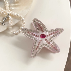 Détail d'une pince à cheveux étoile de mer avec strass roses et gemme centrale carrée