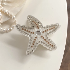Détail d'une pince à cheveux étoile de mer en acétate avec strass sur coquillage