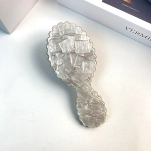 Detailed macro view of pearly white acetate comb with marble texture and wavy edges