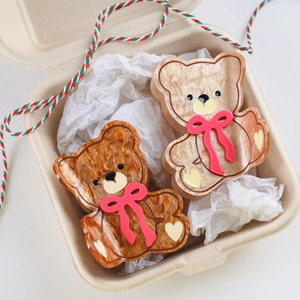 Nahaufnahme der süßen Bär-Haarklammern aus Acetat mit roten Schleifen in Geschenkbox