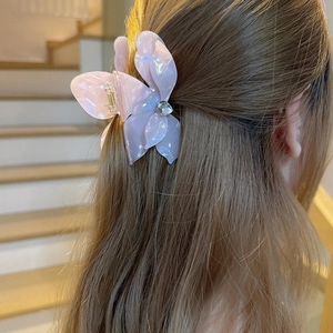 Iridescent flower hair claw clip with crystal center on a deep chestnut hairstyle