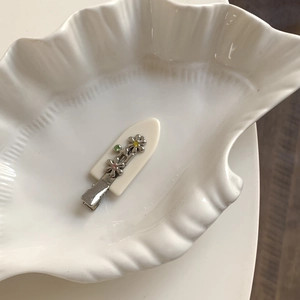 Détail d'une pince à cheveux en acétate avec fleurs en métal argenté et strass colorés