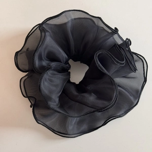 Detail of black organza scrunchie with layered pleats and fine mesh texture for ponytail