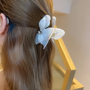 Elegant white floral hair claw clip with rhinestones worn on brown wavy hair