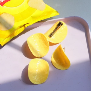 Detailed view of four realistic yellow potato chip hair clips with gold metal duckbill clips