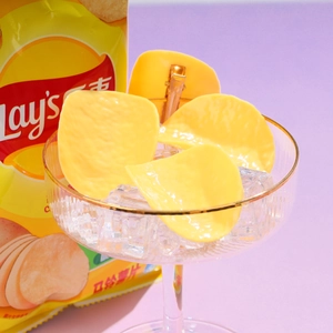 Detail showing creative yellow potato chip hair clips arranged in a glass with ice cubes
