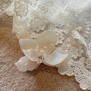 Detailed macro view of pearlescent floral hair claw with sparkling central crystal