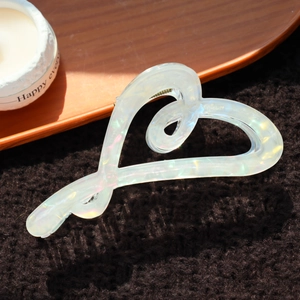 Détail macro d'une pince à cheveux en forme de cœur crème avec texture marbrée