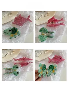 Detail view of acetate sea animal hair claws showing pink dolphin and green turtle patterns