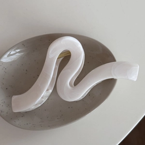 Detail of large ink texture hair claw clip with cream marble pattern and gold spring